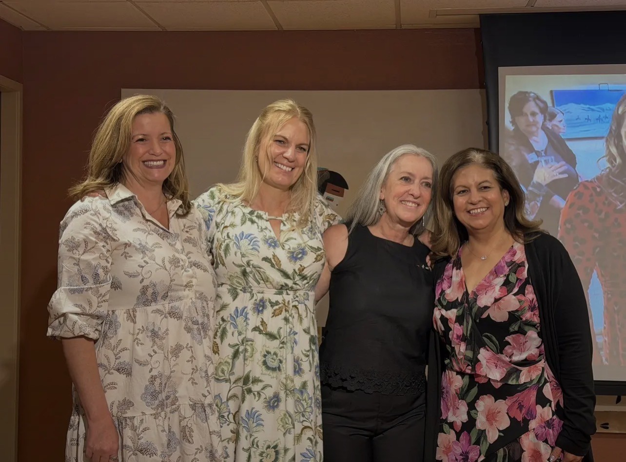 Four individuals standing together indoors