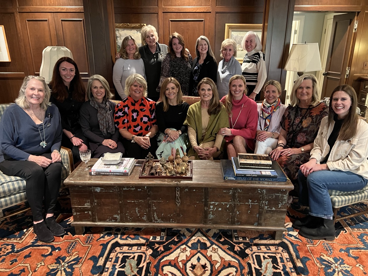 Multiple people posed indoors near an ornate rug and coffee table