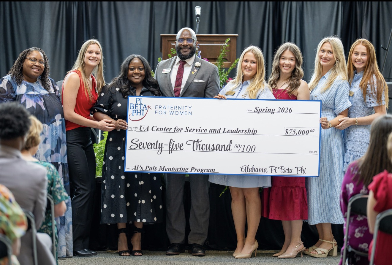 A group of members and community leaders holding a giant check for $75,000