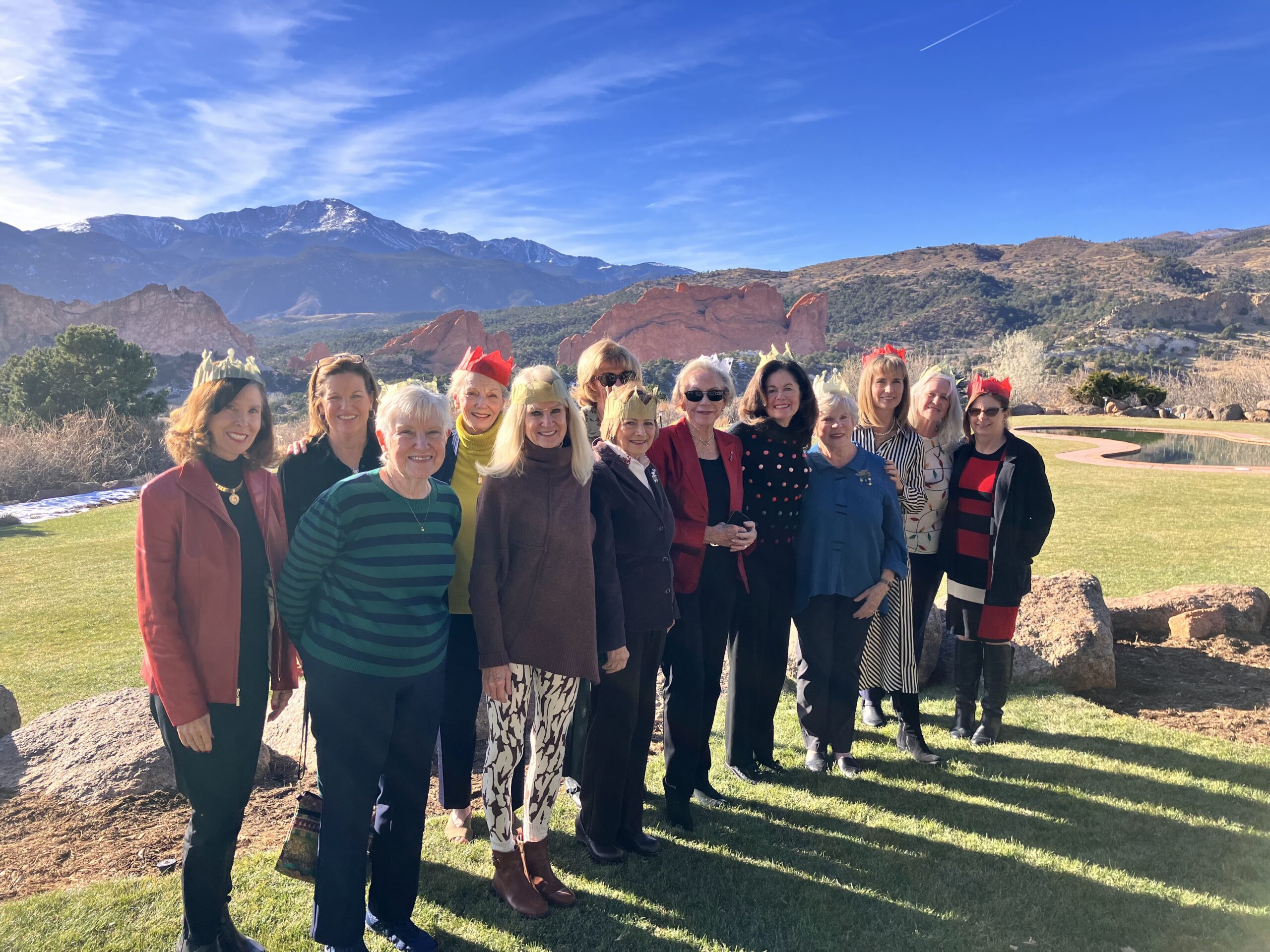 Several alumnae members standing outside with a blue sky and mountains in the background