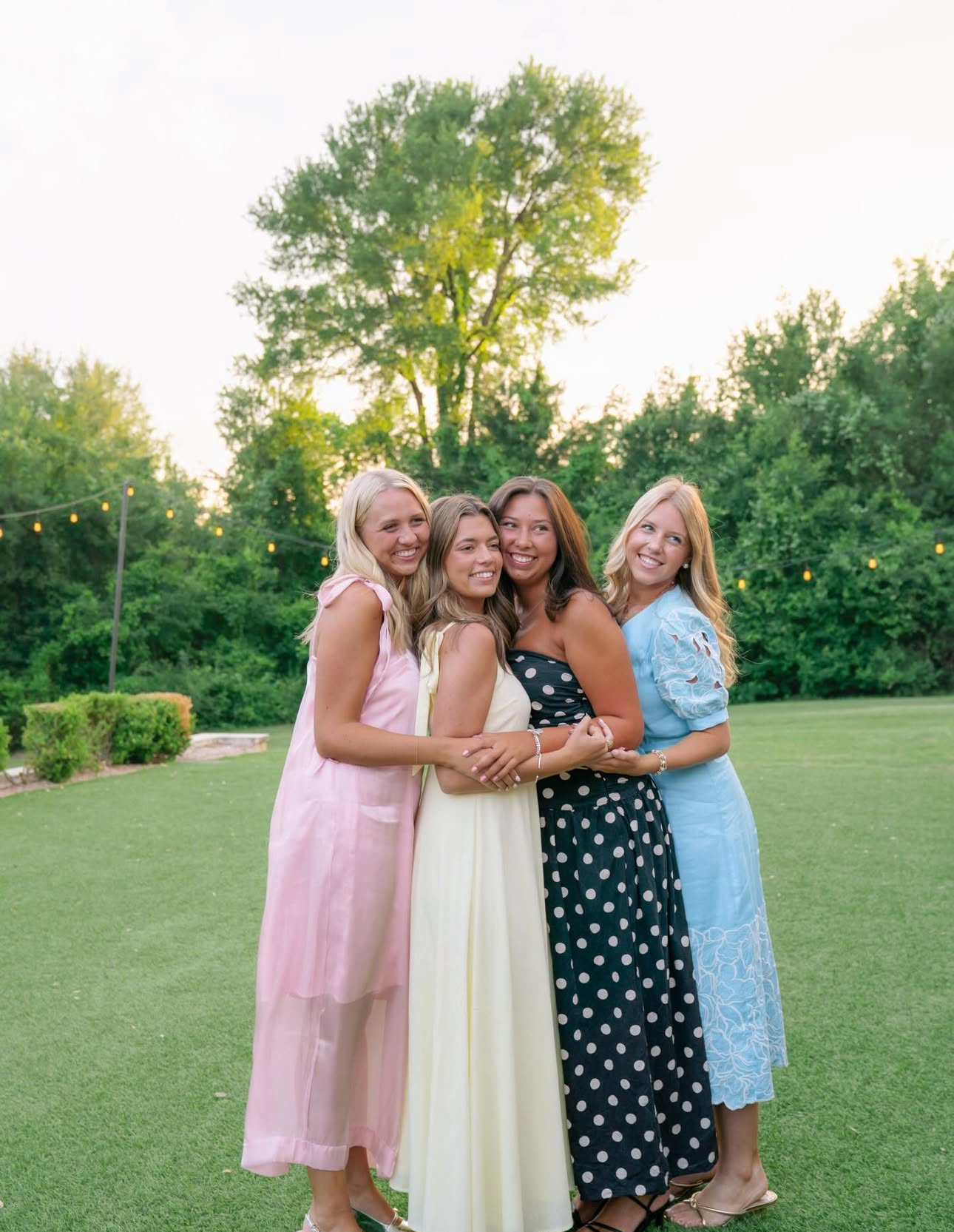 Four individuals standing outdoors hugging