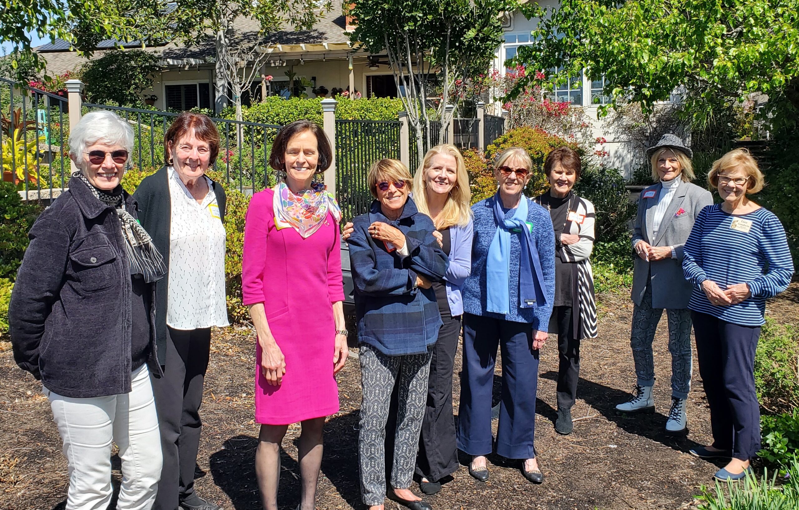 Nine alumnae members standing outside with green trees in the background