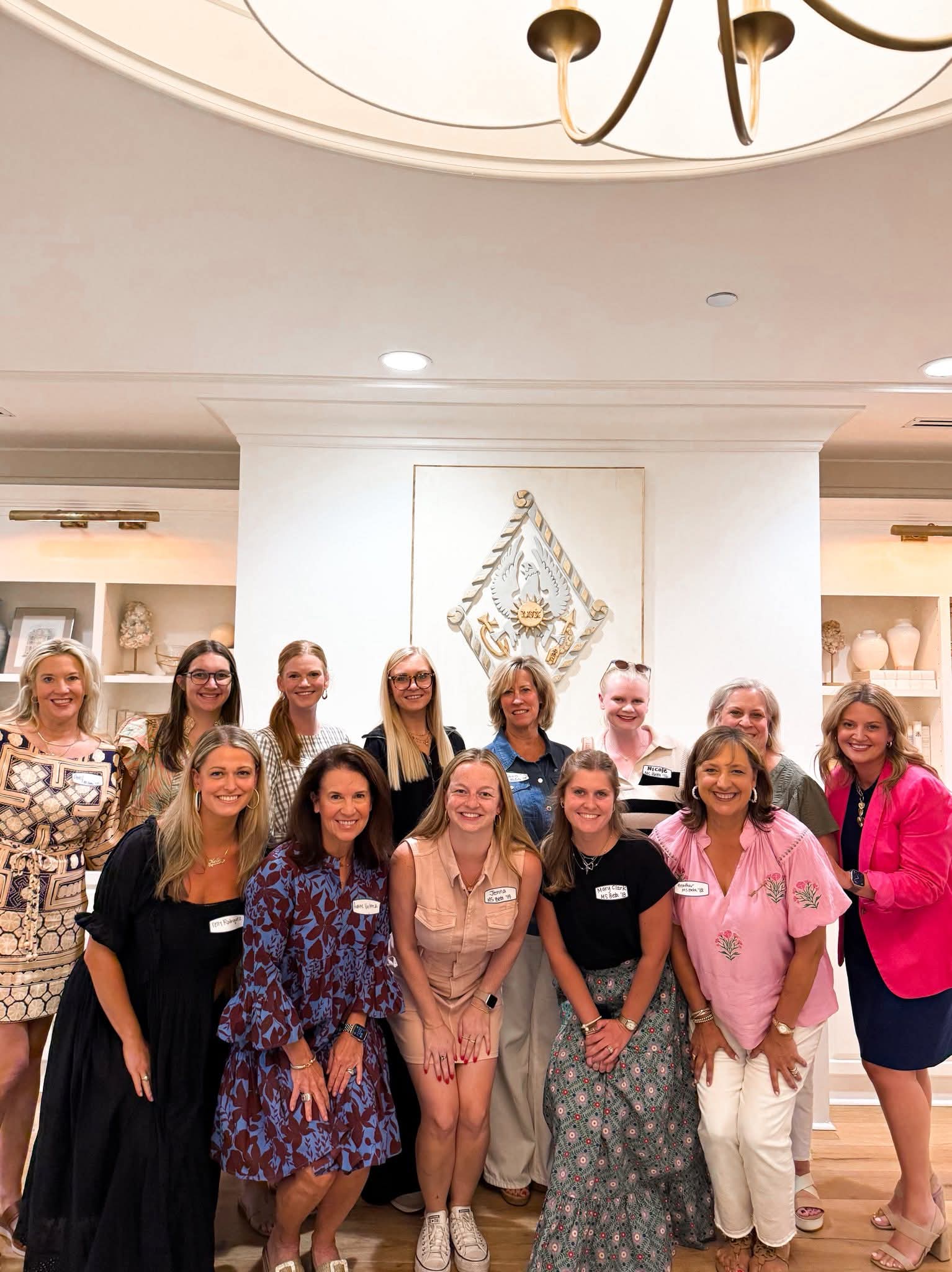 Several members standing in front of a wall with the Pi Phi crest