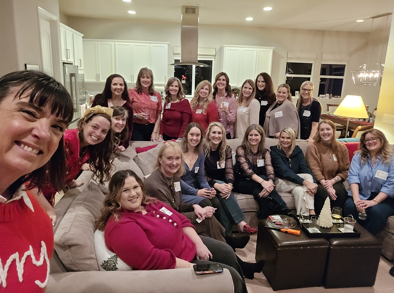 Self-taken image of a woman posed indoors with a large group of individuals.