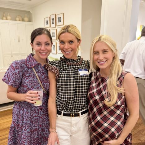 Three Pi Beta Phi alumnae smiling together at an indoor networking event, wearing patterned tops and casual attire