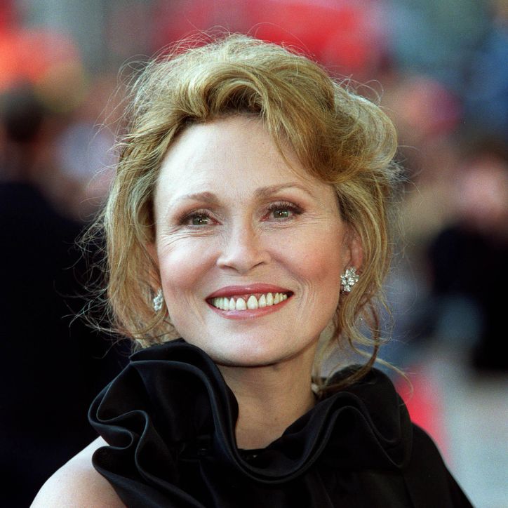 Headshot of Faye Dunaway smiling at an event, wearing a black ruffled dress and diamond earrings