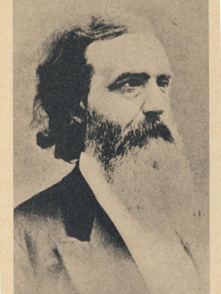 Black and white historical portrait photograph of a bearded man in a Victorian-era suit