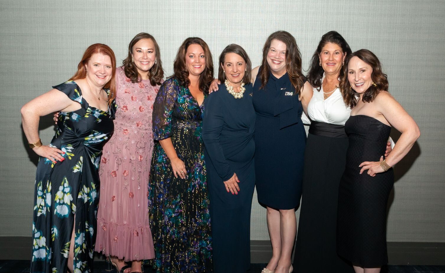 Seven Pi Beta Phi leadership team members smiling together in formal attire at an evening event