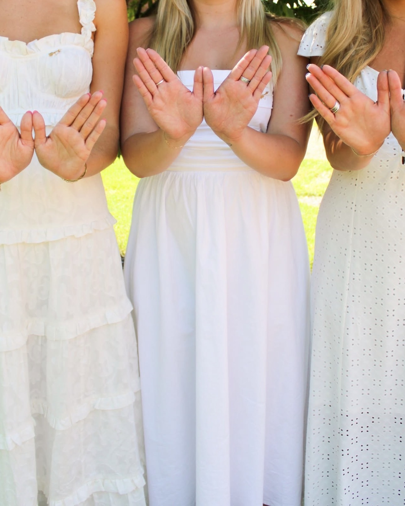 Three members wearing white and making angel wings with their hands