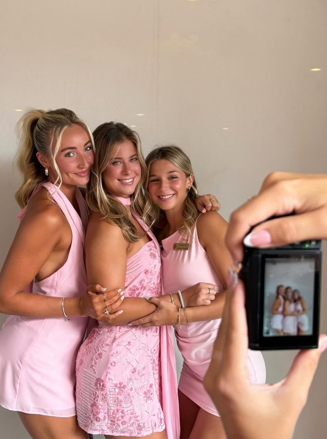 Three individuals posting for a photo and someone taking their photo with a digital camera