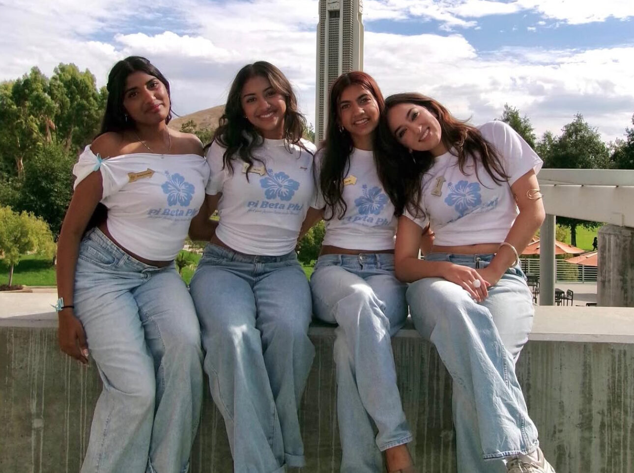 Four individuals sitting on a ledge outdoors