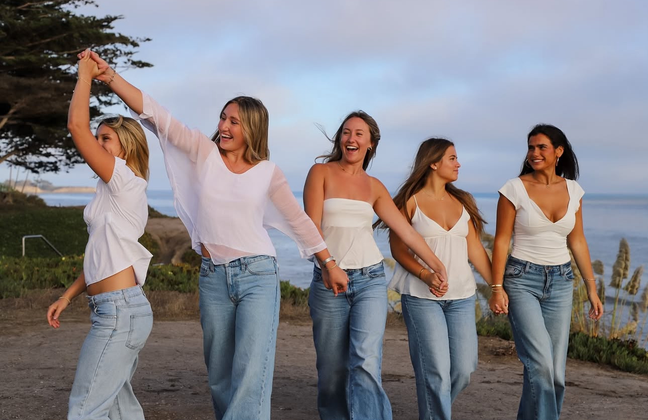 Five individuals walking wearing white shirts and blue jeans
