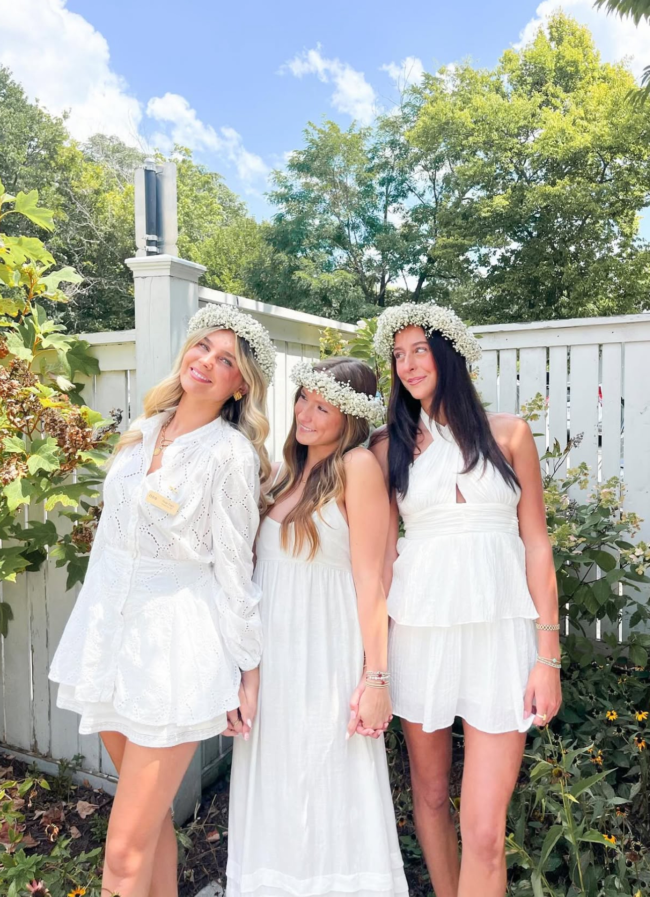 Three members standing outdoors wearing white