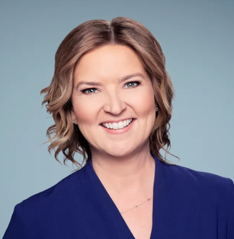 Professional headshot of Christine Romans wearing a navy blue shirt in front of a light blue background