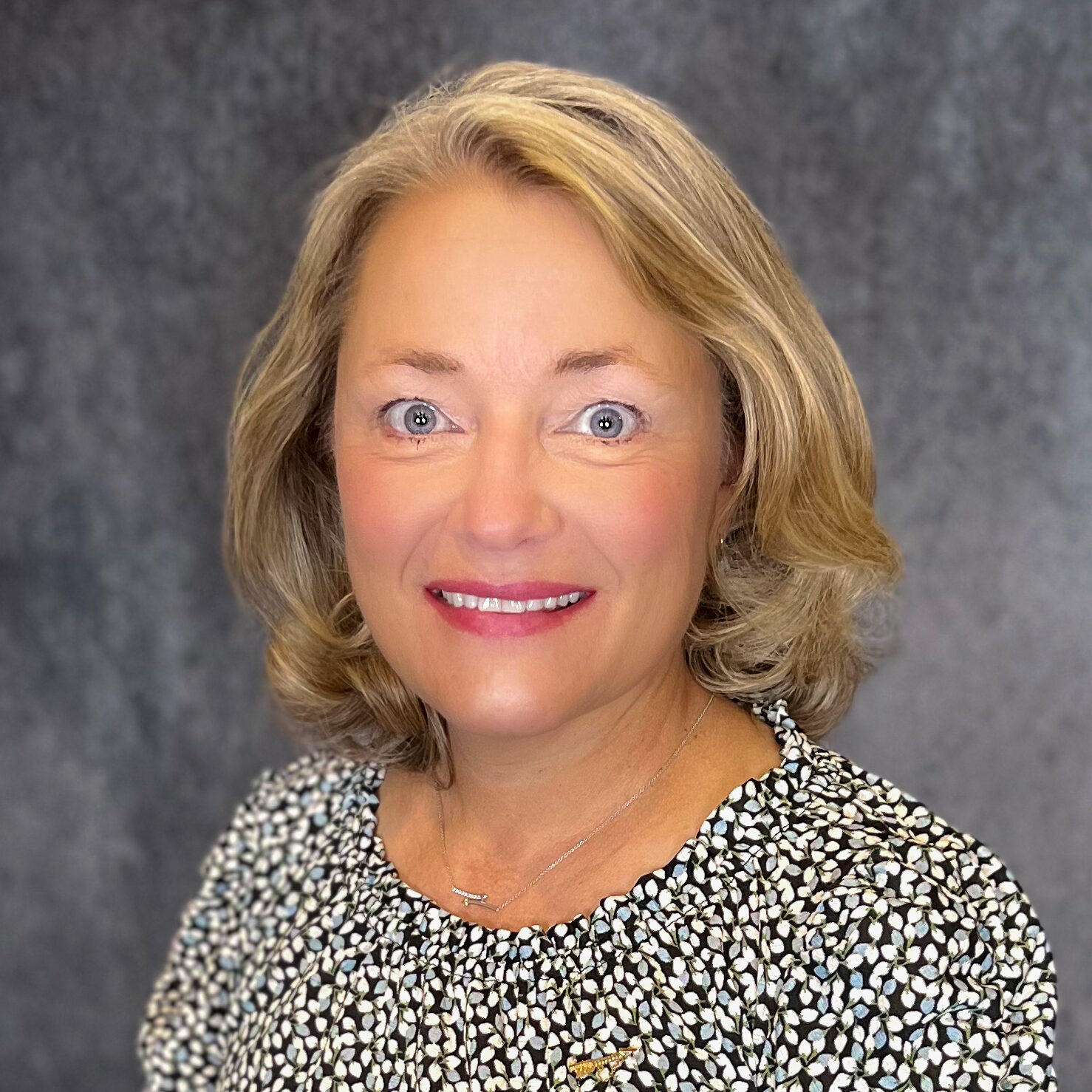 Professional headshot of Ann Wiley wearing a black and white patterned blouse