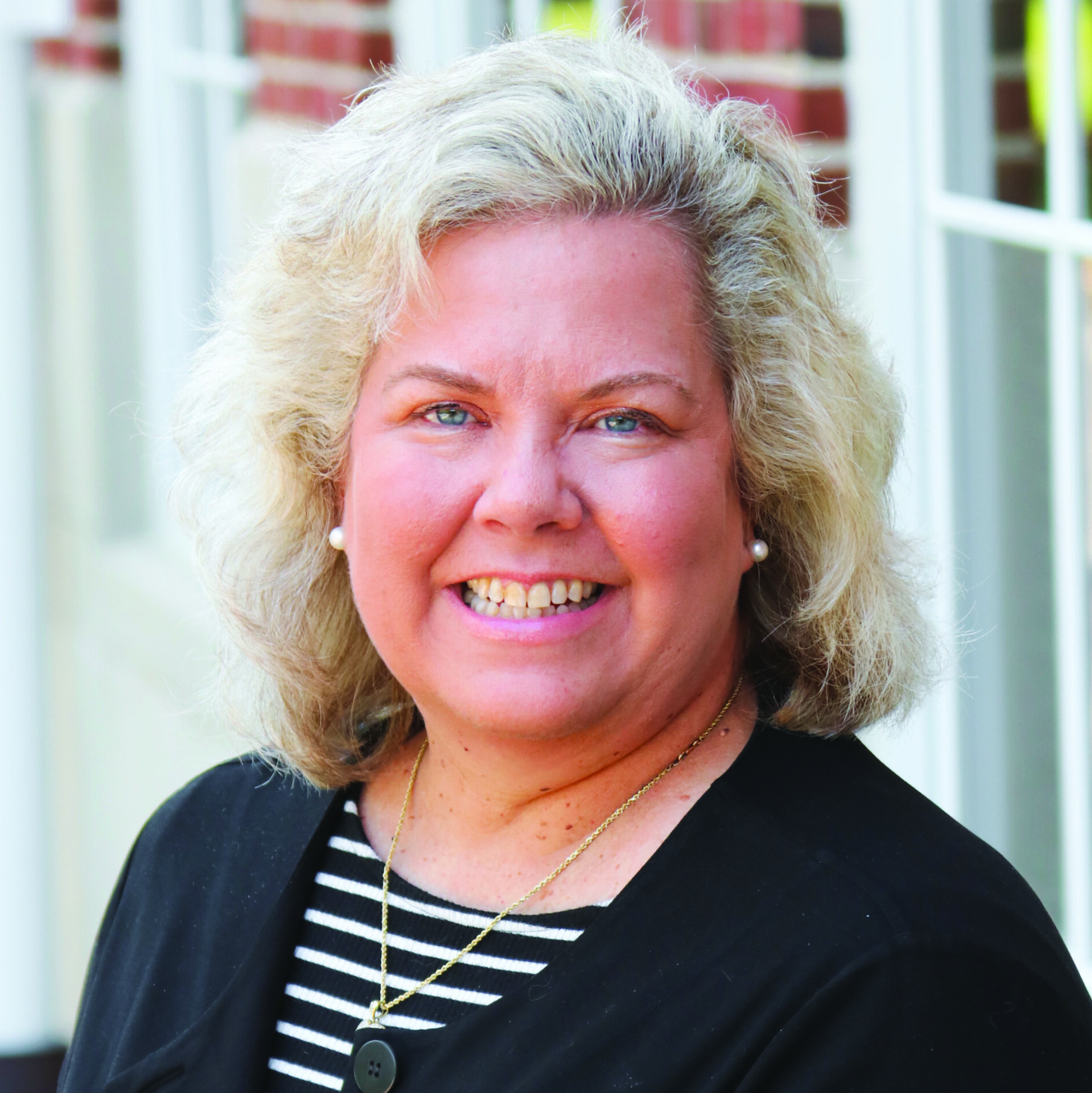 Professional headshot of Kim Durand wearing a black jacket and black and white striped blouse