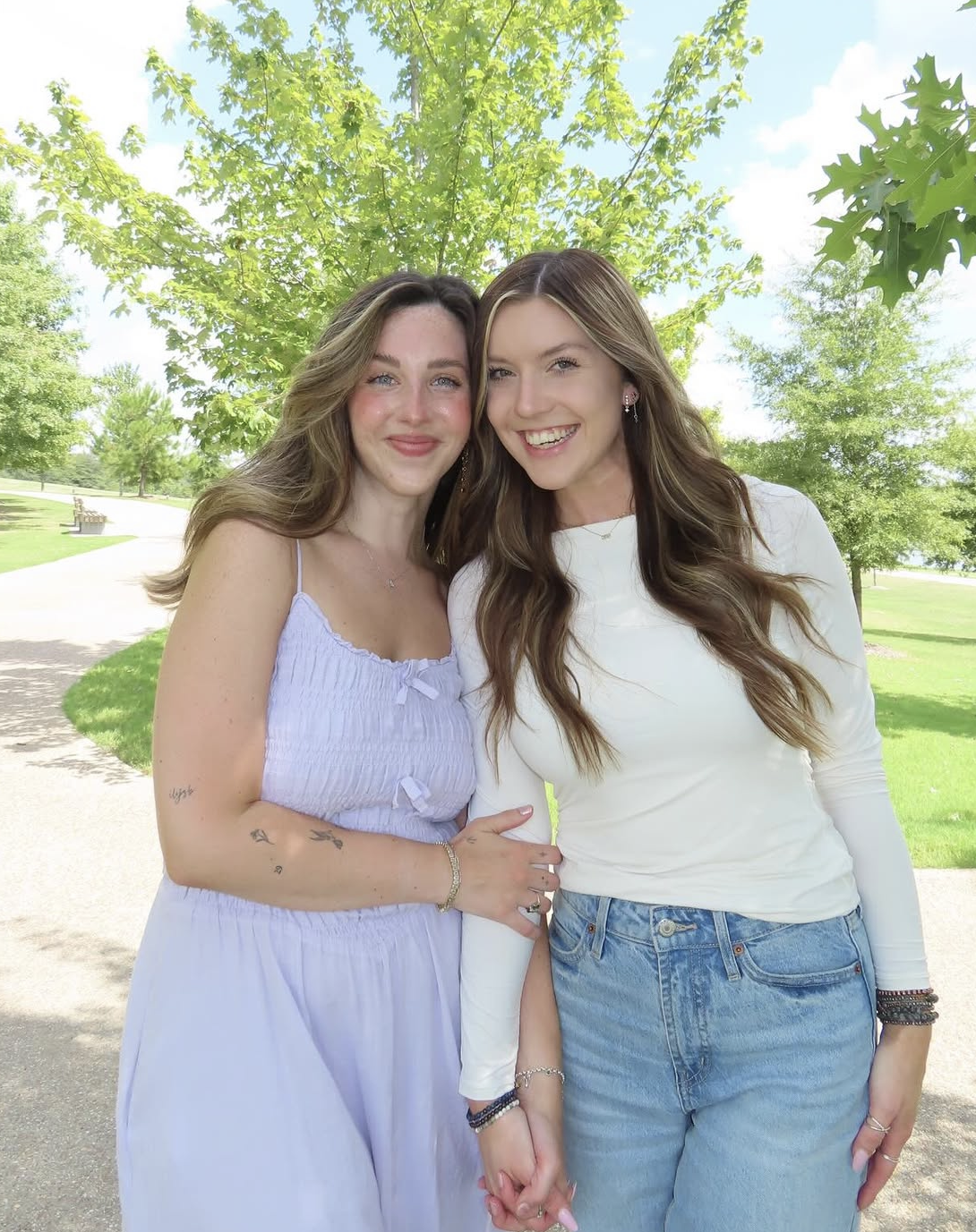 Two members standing on a sidewalk in front of several trees