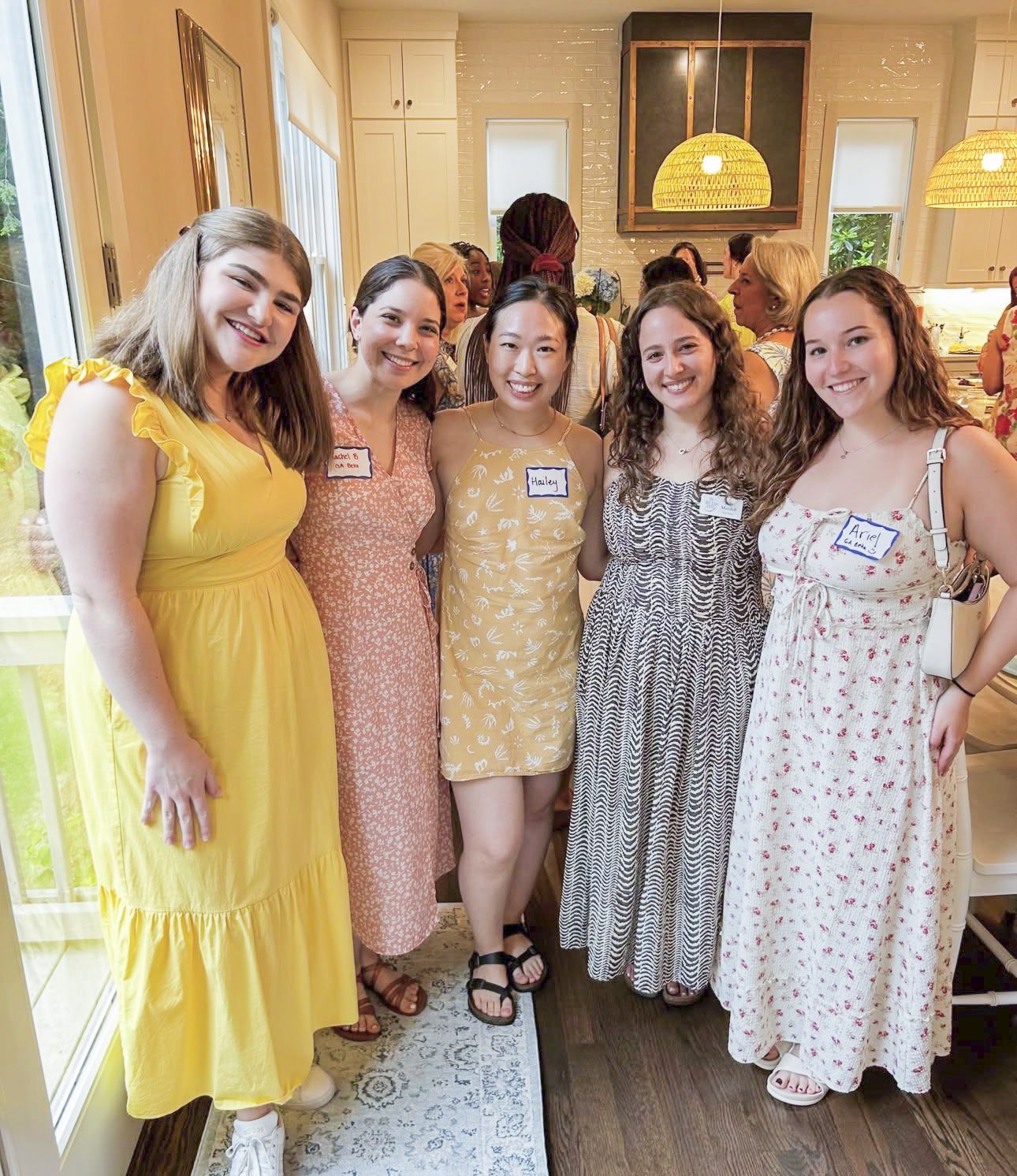 Five individuals wearing dresses and standing indoors