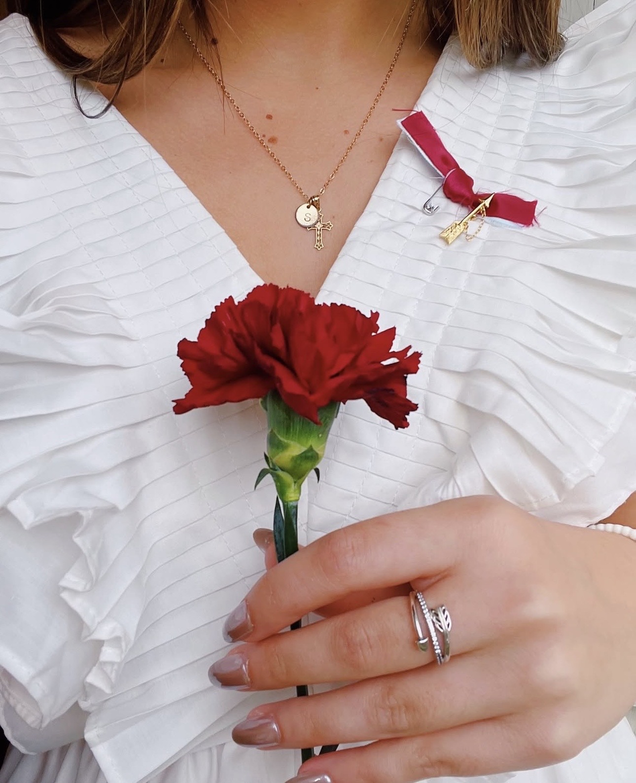 An individual wearing white and holding a wine carnation