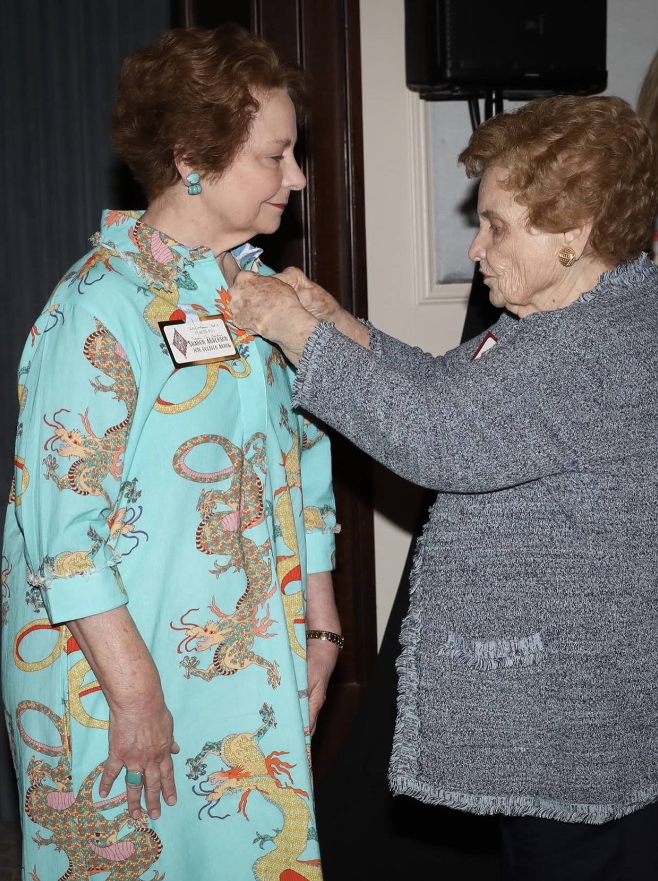 One individual placing a pin on another