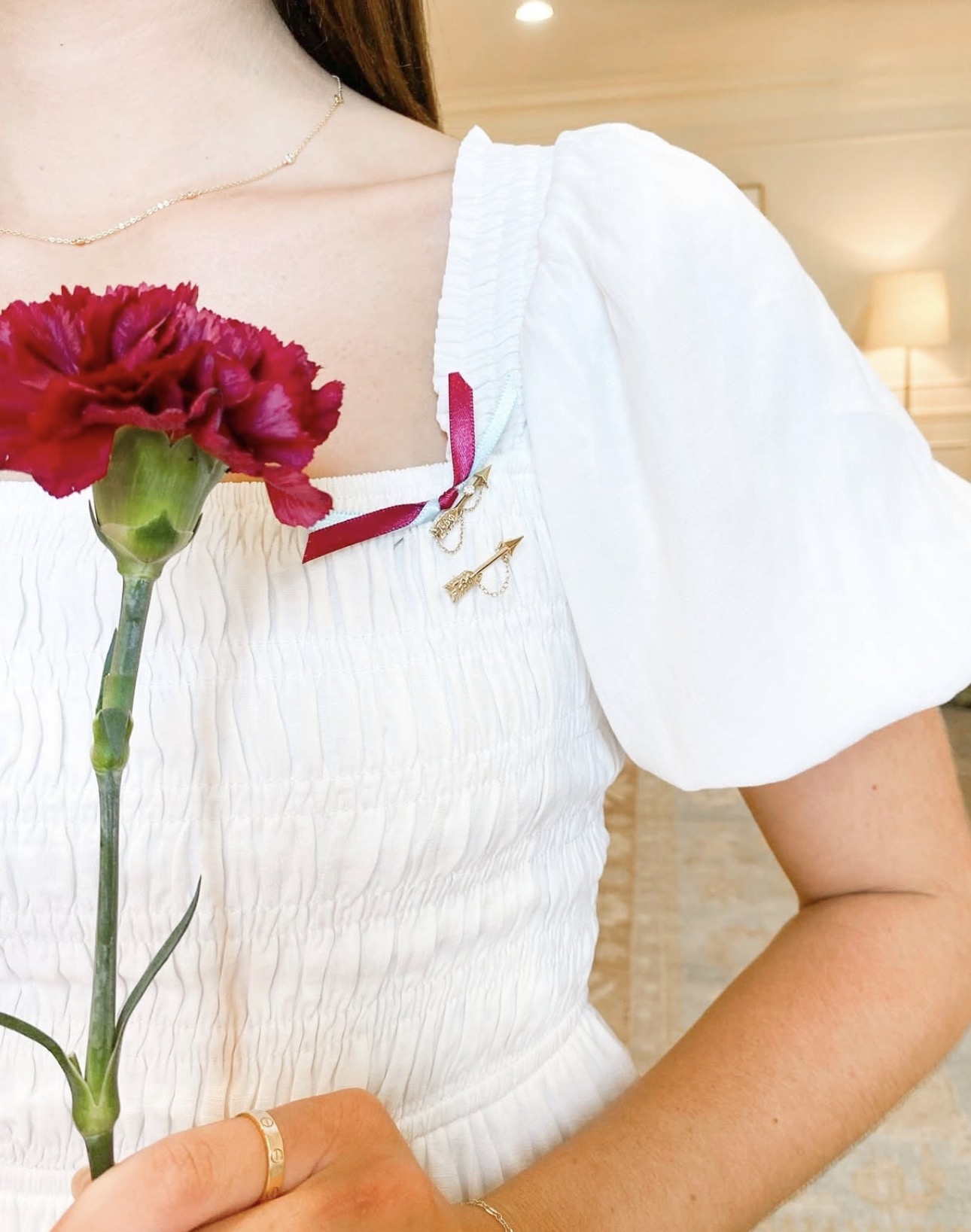 An individual wearing a white dress and holding a wine carnation