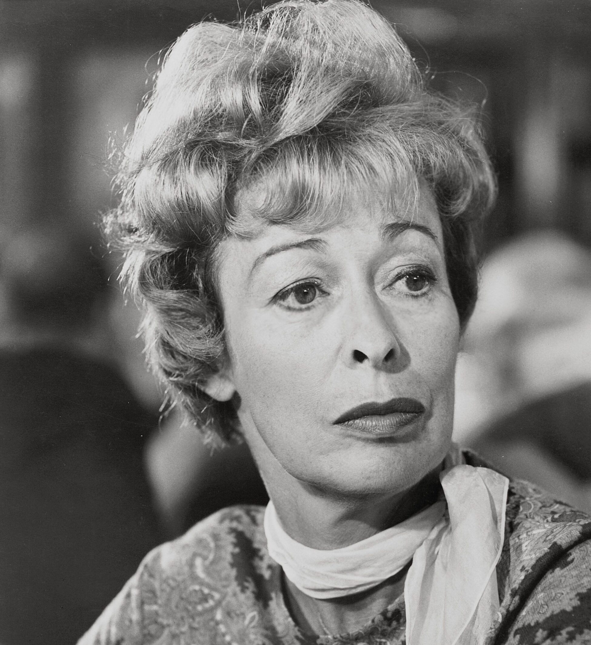 Historical black and white headshot of Eileen Heckart Yankee wearing a light colored blouse and white scarf in front of a blurred background