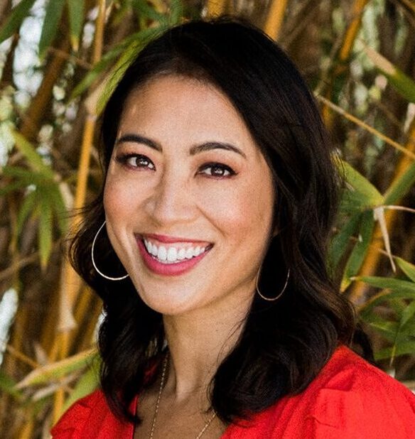 Professional headshot of Elise Hu wearing a red shirt in front of trees