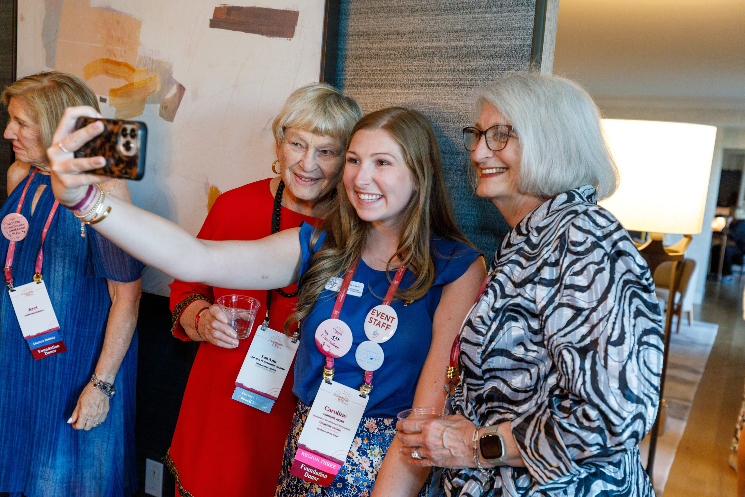 Three individuals standing indoors and taking a selfie