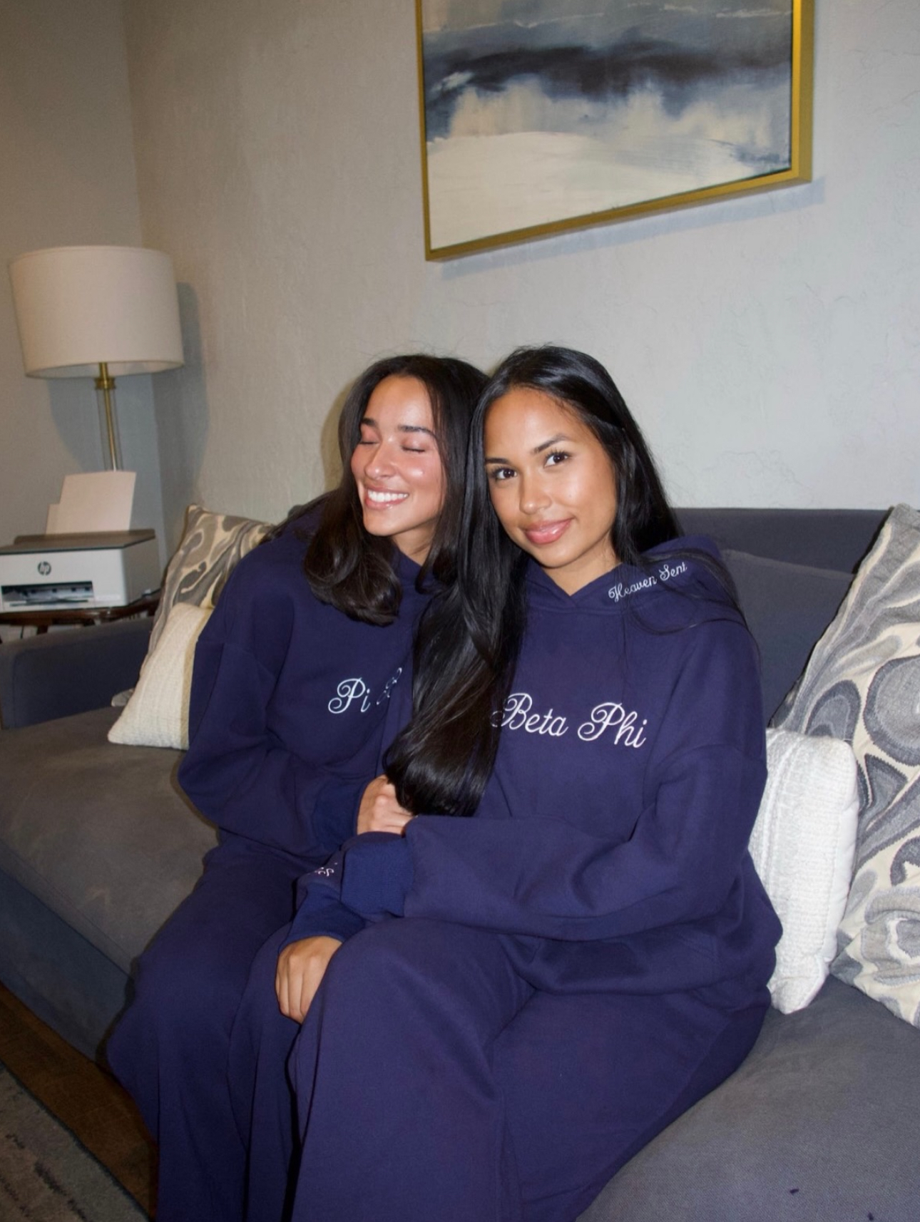 Two individuals wearing blue sweatsuits sitting on a couch