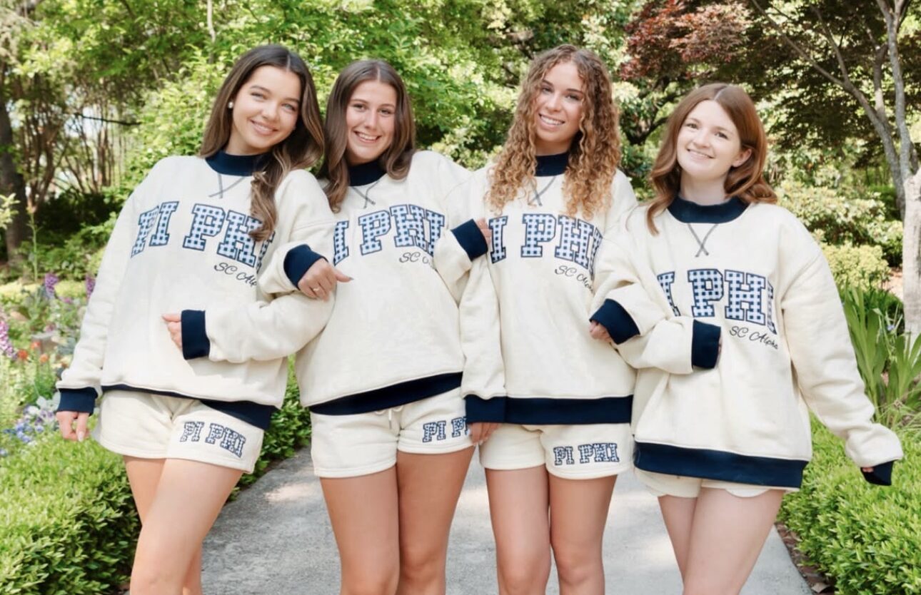 Four members wearing matching sweat sets that say Pi Phi