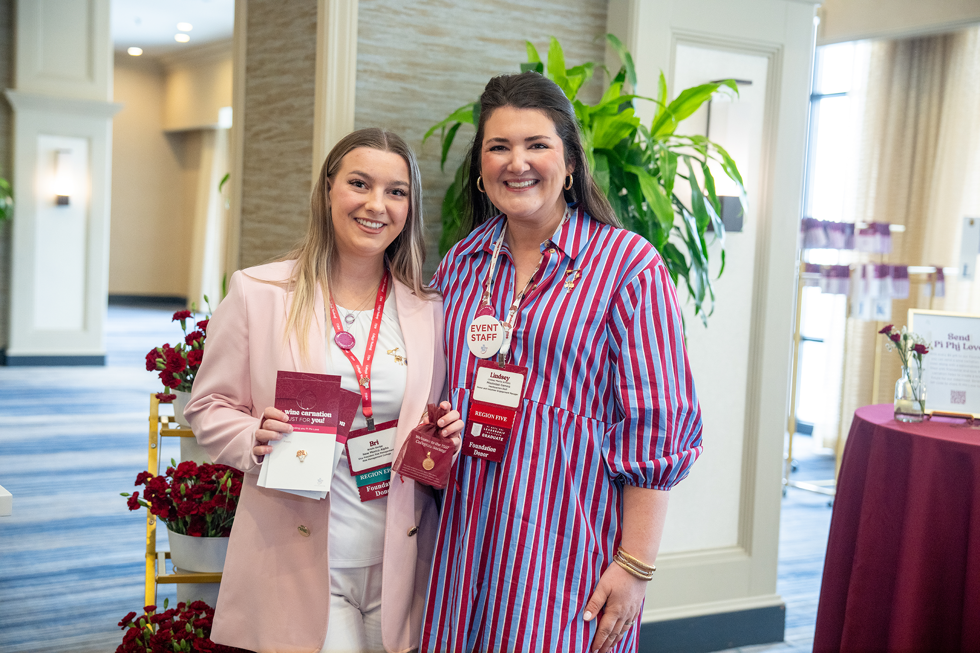 Two members holding wine carnation pins on cards