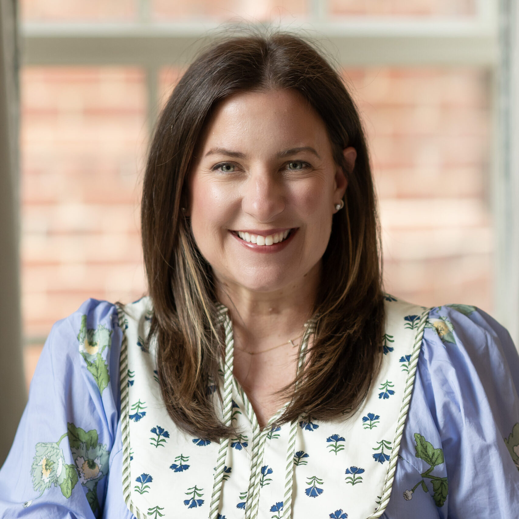 Professional headshot of MaryKeely Smith wearing a blue and white patterned dress