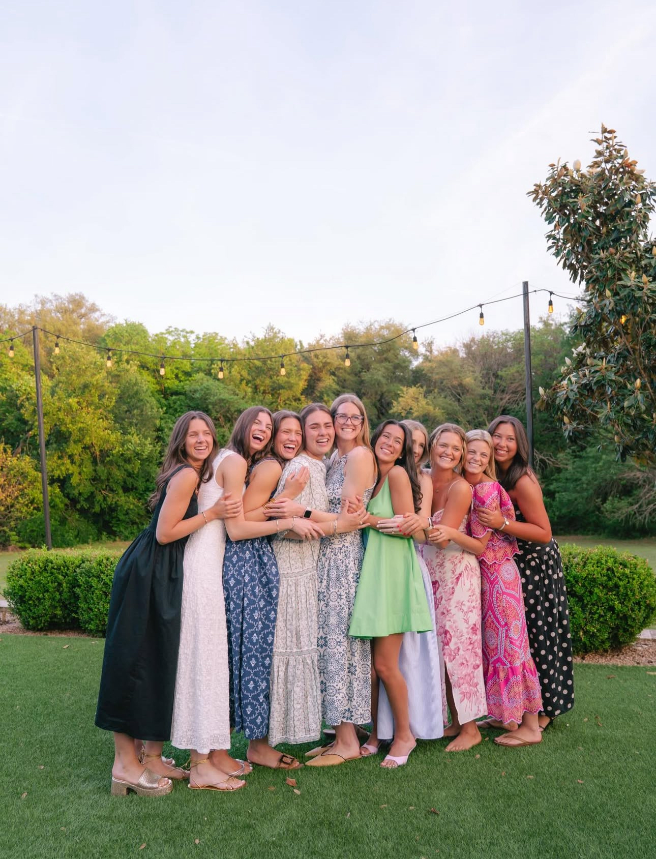 Ten individuals standing outdoors hugging
