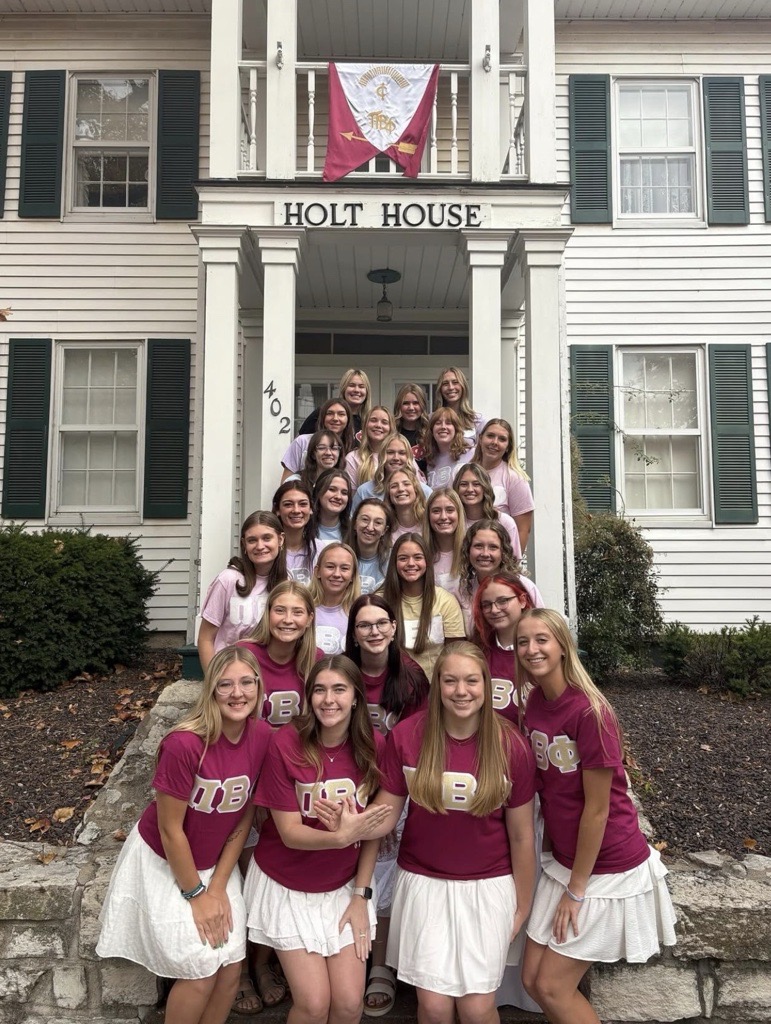 A group of members wearing matching shirts standing on the stairs in front of Holt House