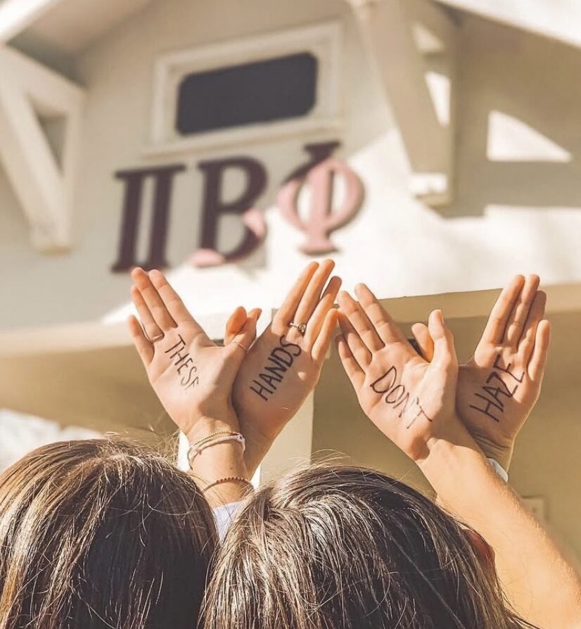 Two members making angel wings with their hands that say these hands don't haze
