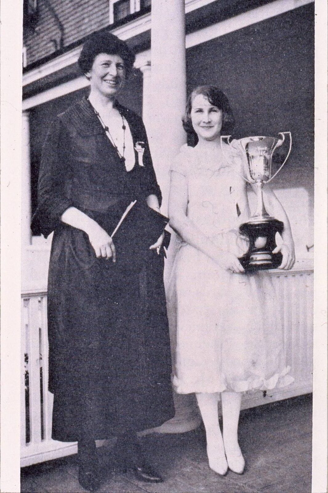 First recipient of Balfour Cup; member holding a trophy standing besides another member