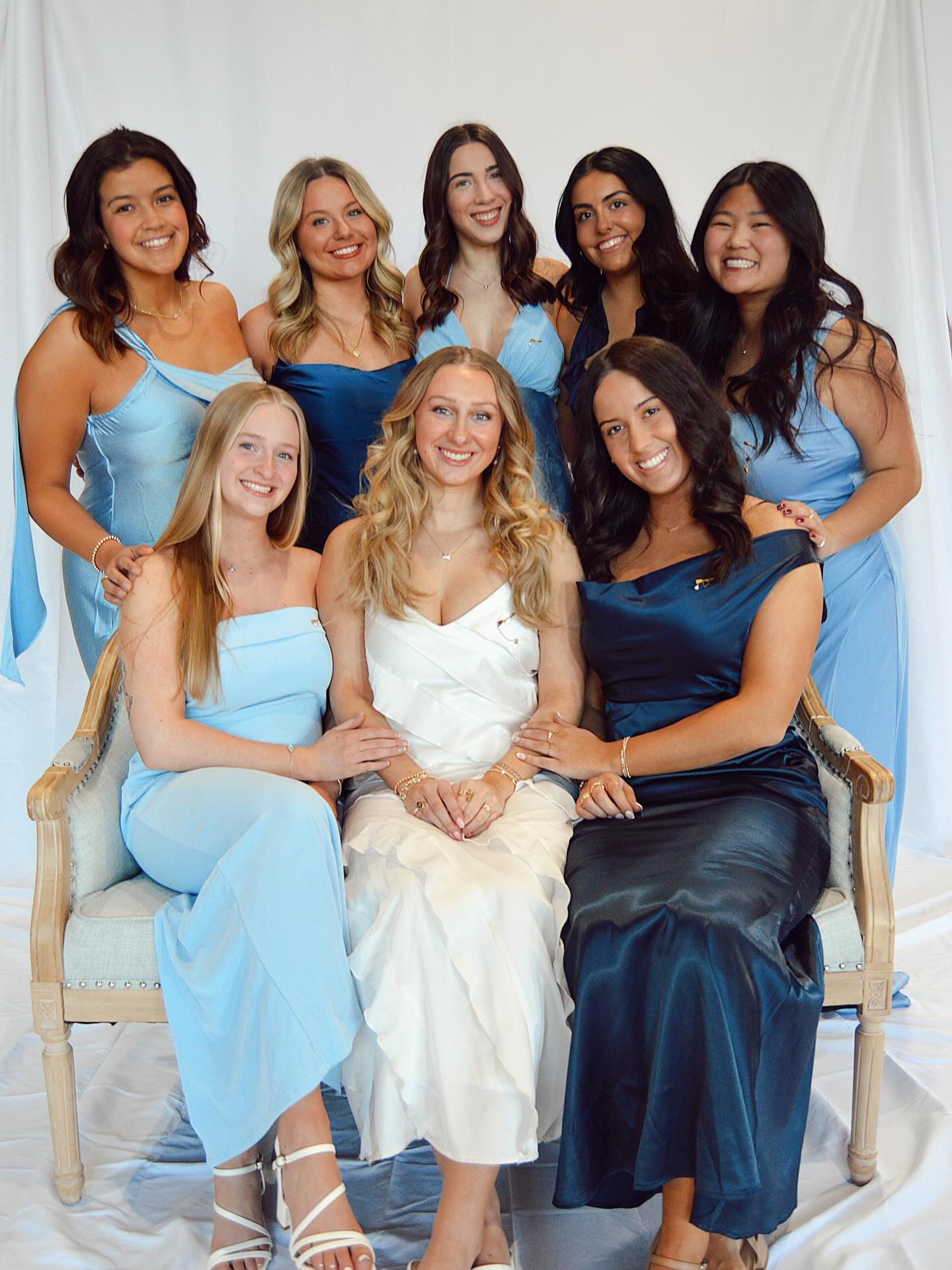 10 members wearing shades of blue and white dresses