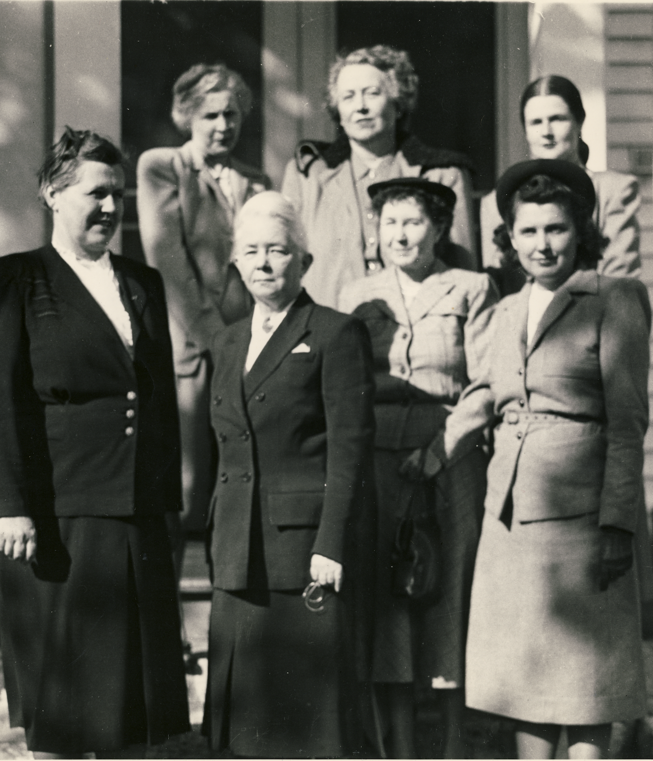 Black and white photo of seven members standing in front of Holt House