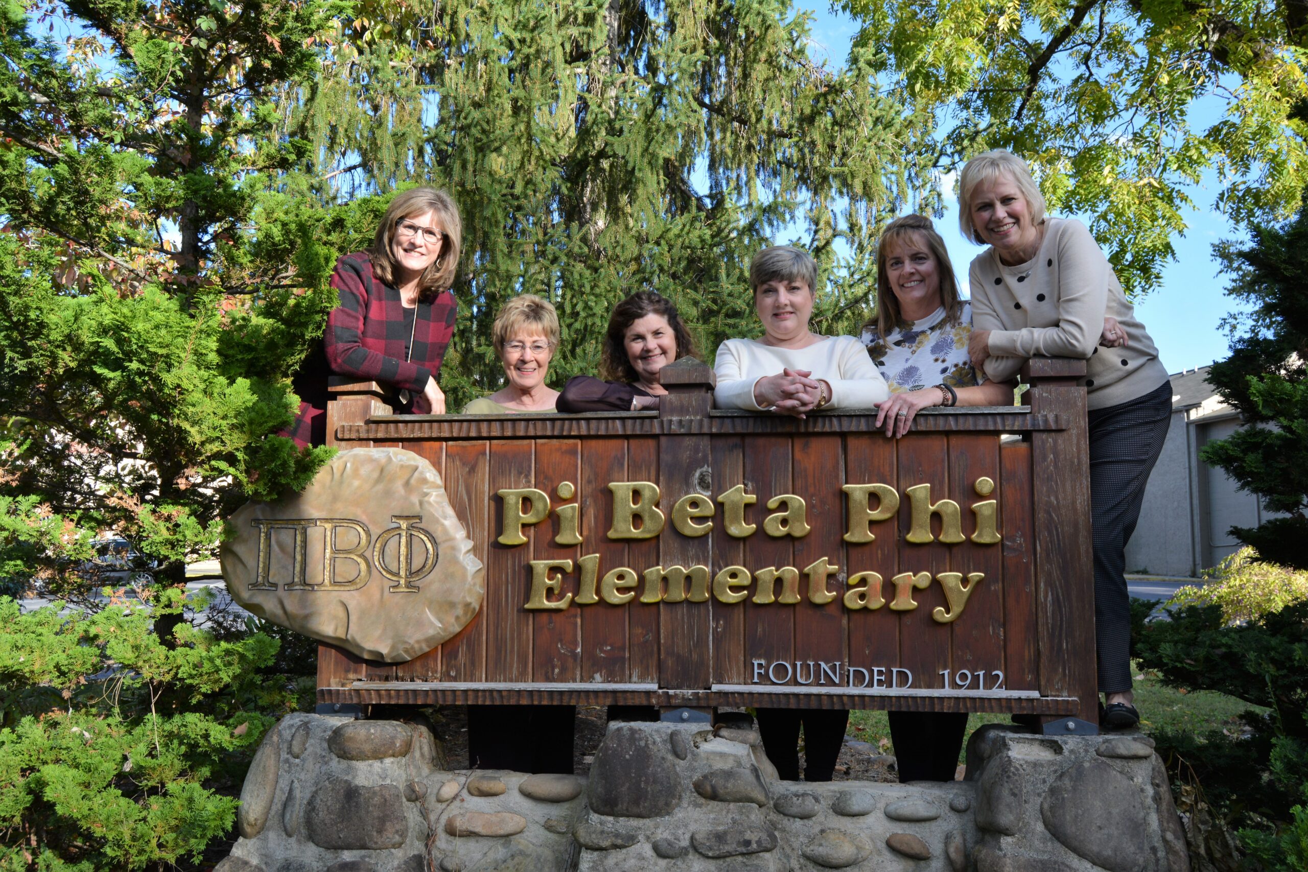 Six members standing behind a sign that says Pi Beta Phi Elementary