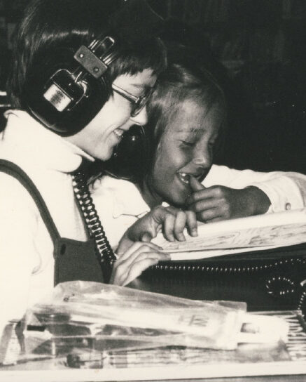 A member and child wearing headphones reading
