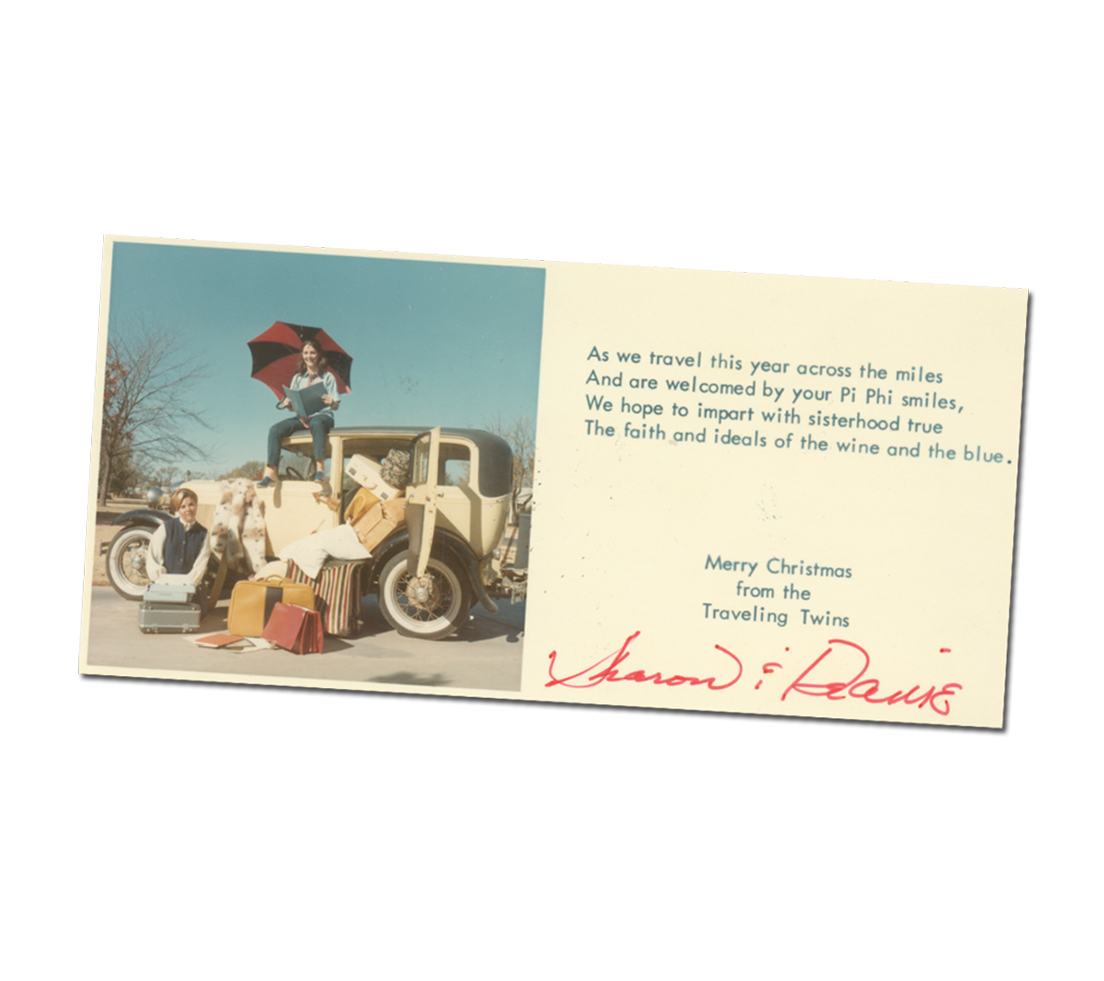 Card with a photo of two members sitting next to a car that is overflowing with luggage, there is a note signed by the Traveling Twins