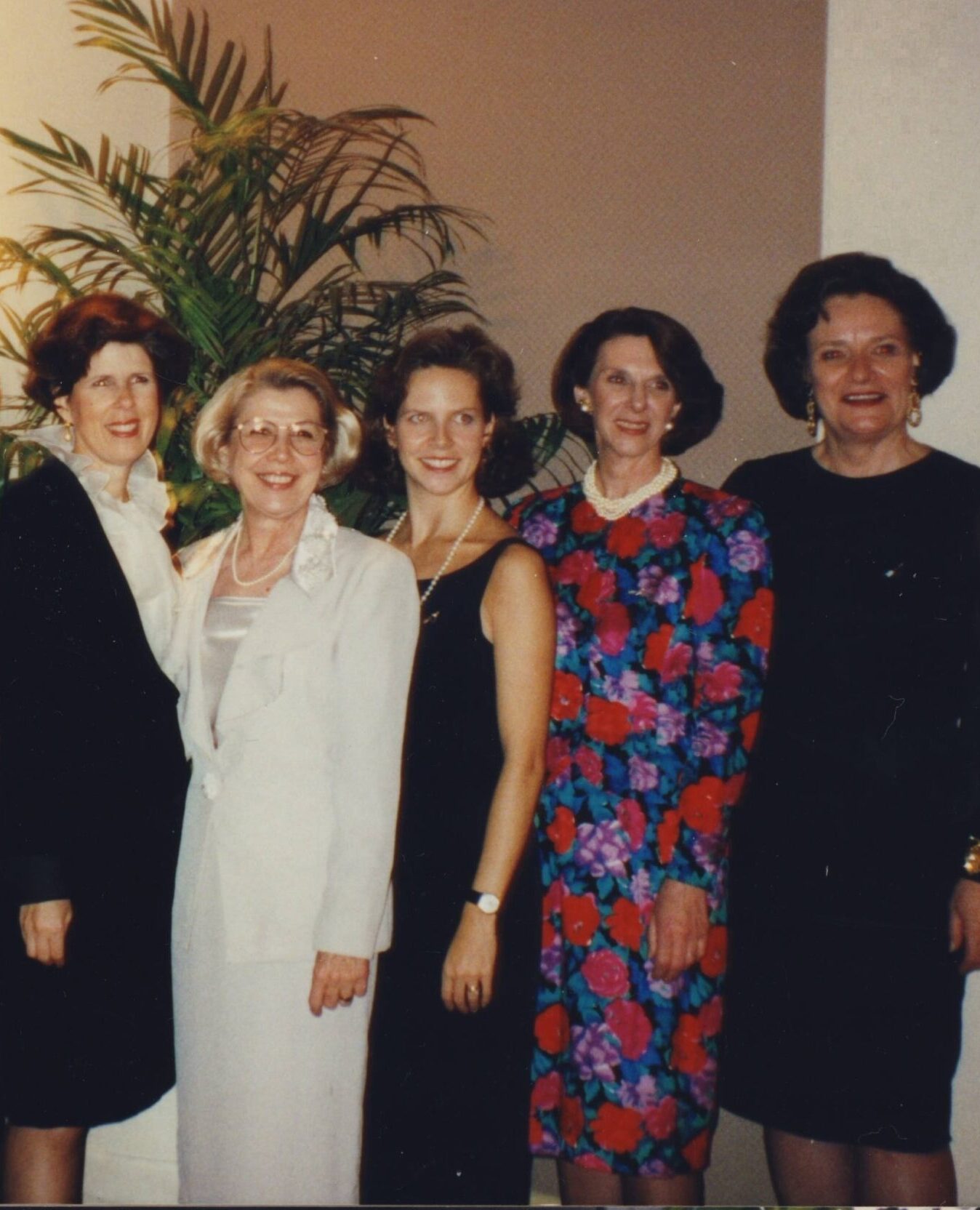 An older photo with several members in a line smiling toward the camera
