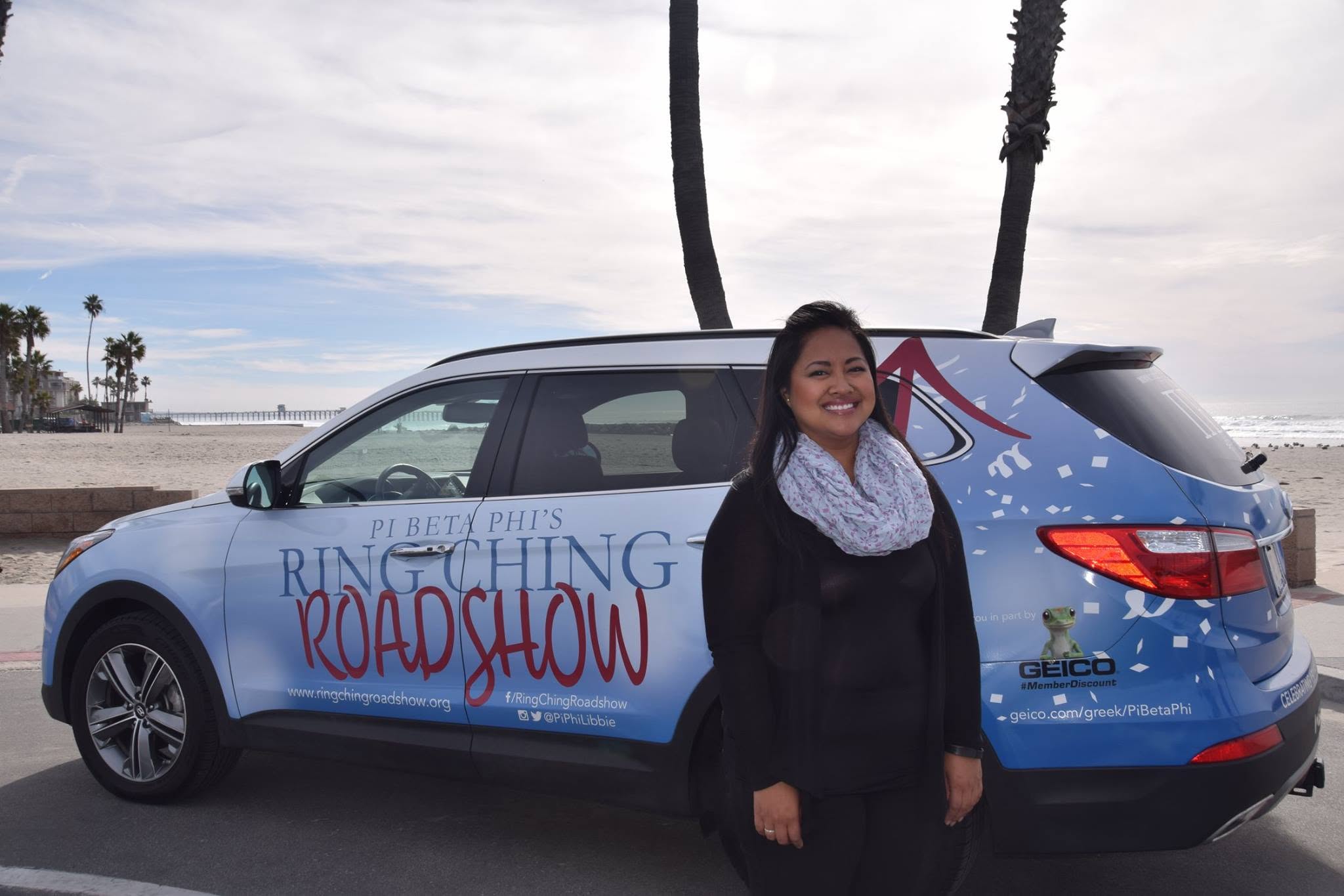 One member standing in front of a branded car that says Pi Beta Phi's Ring Ching Roadshow