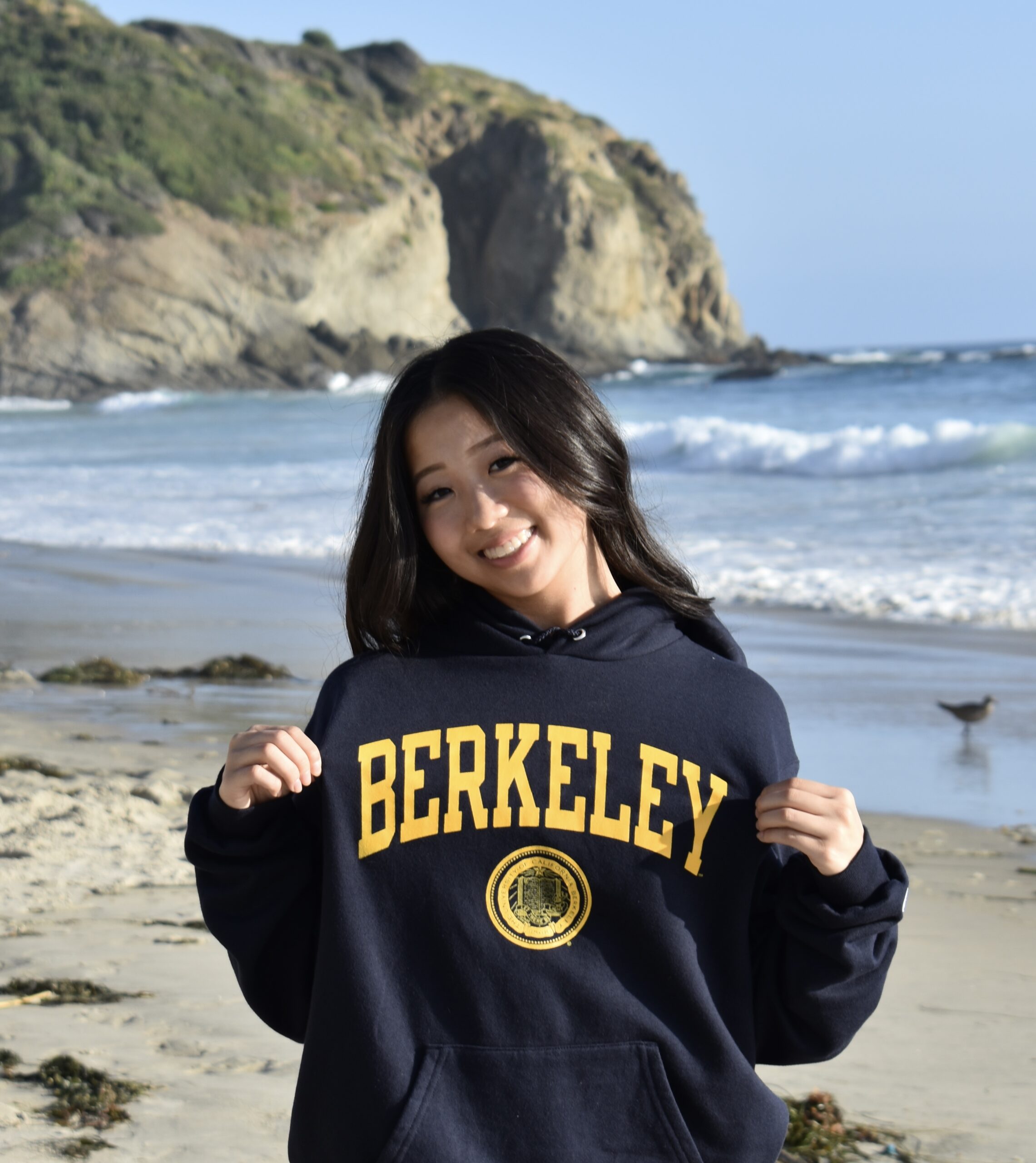 Member standing on the beach wearing a Berkeley sweatshirt