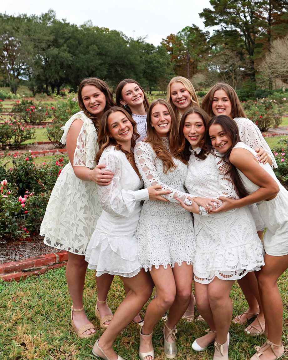 Eight members standing outdoors in white dresses