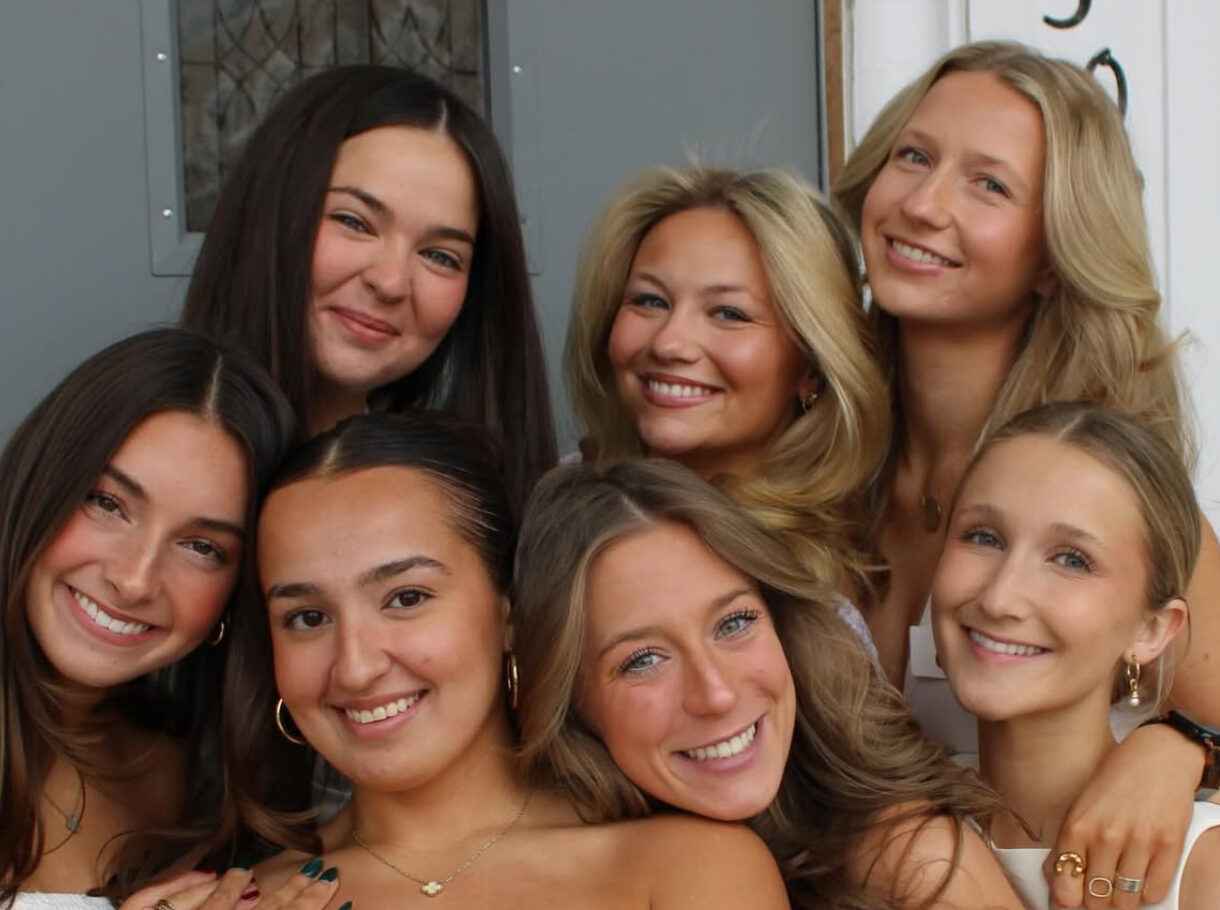 Seven individuals wearing white and hugging