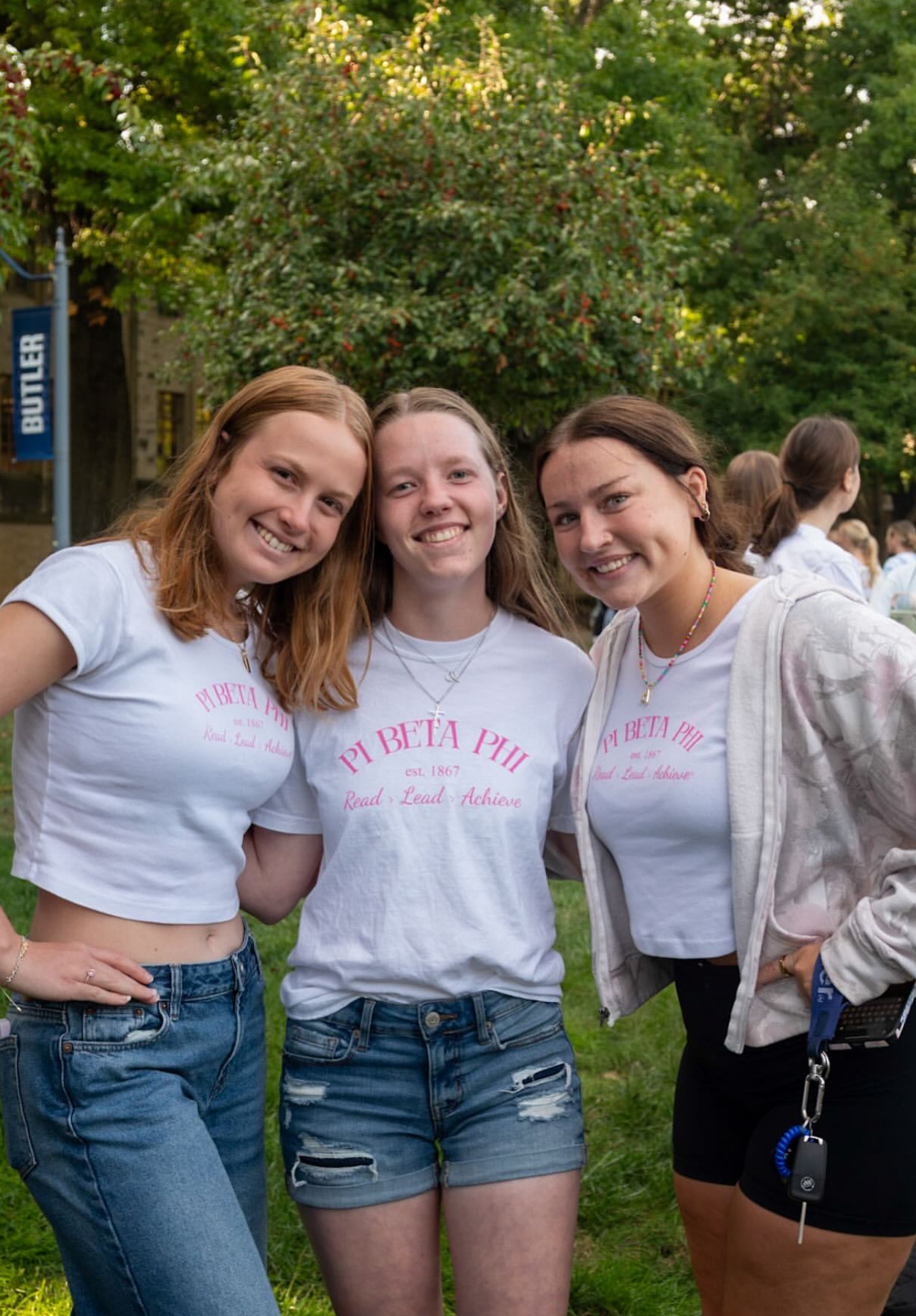 Three individuals standing in front of trees