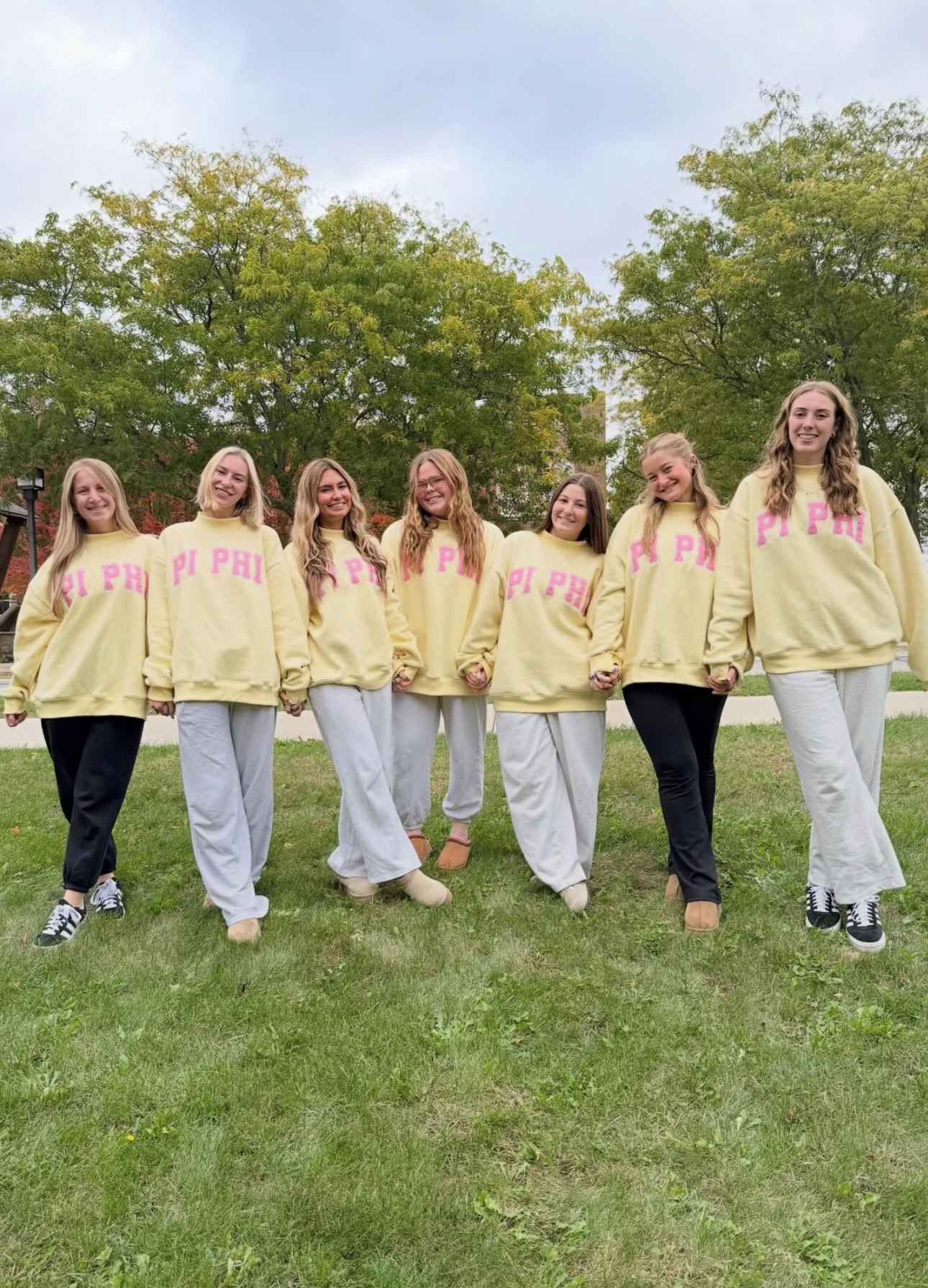 Seven individuals walking wearing matching yellow sweatshirts