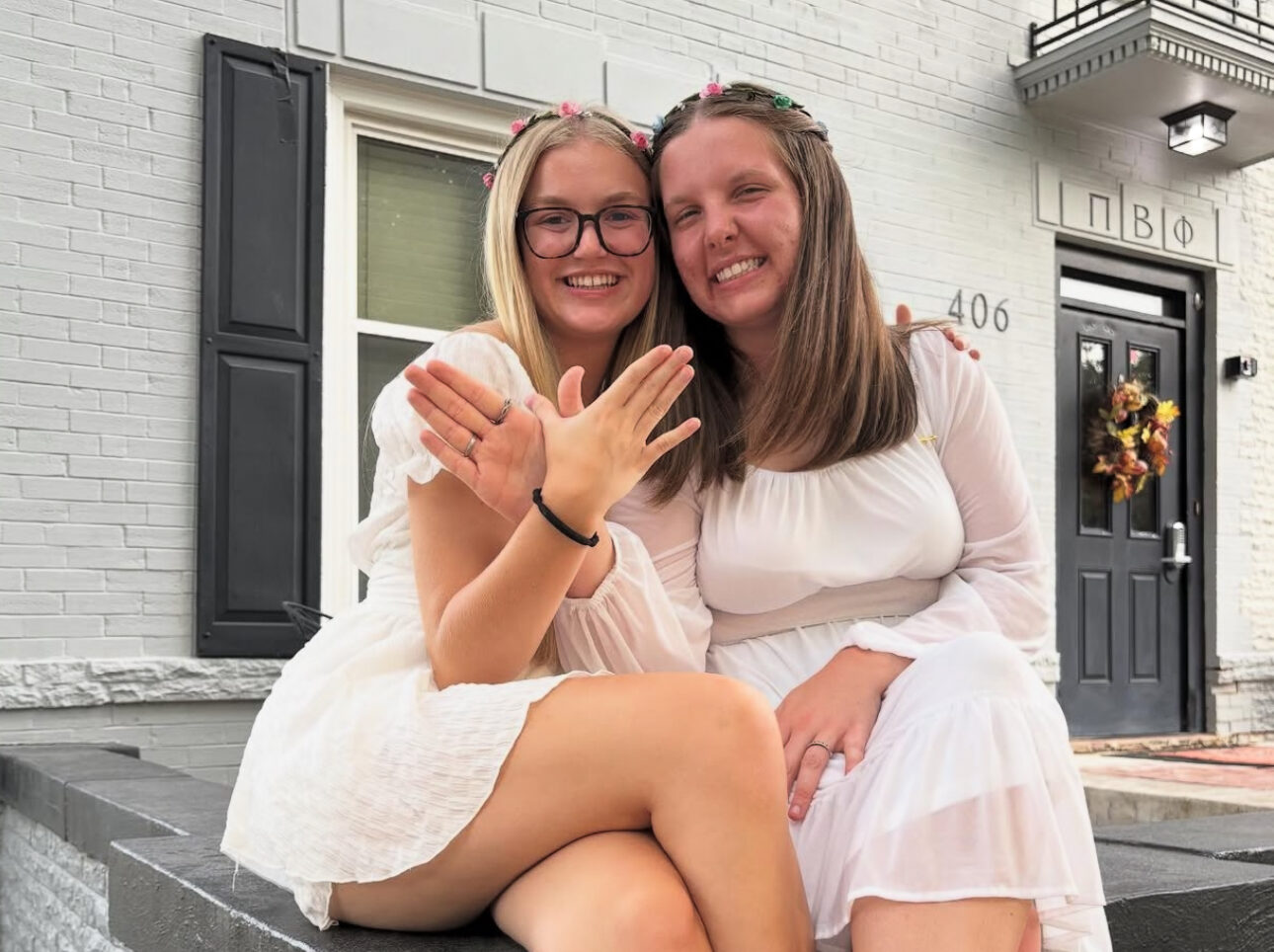Two individuals sitting on a porch and making angel wings with their hands