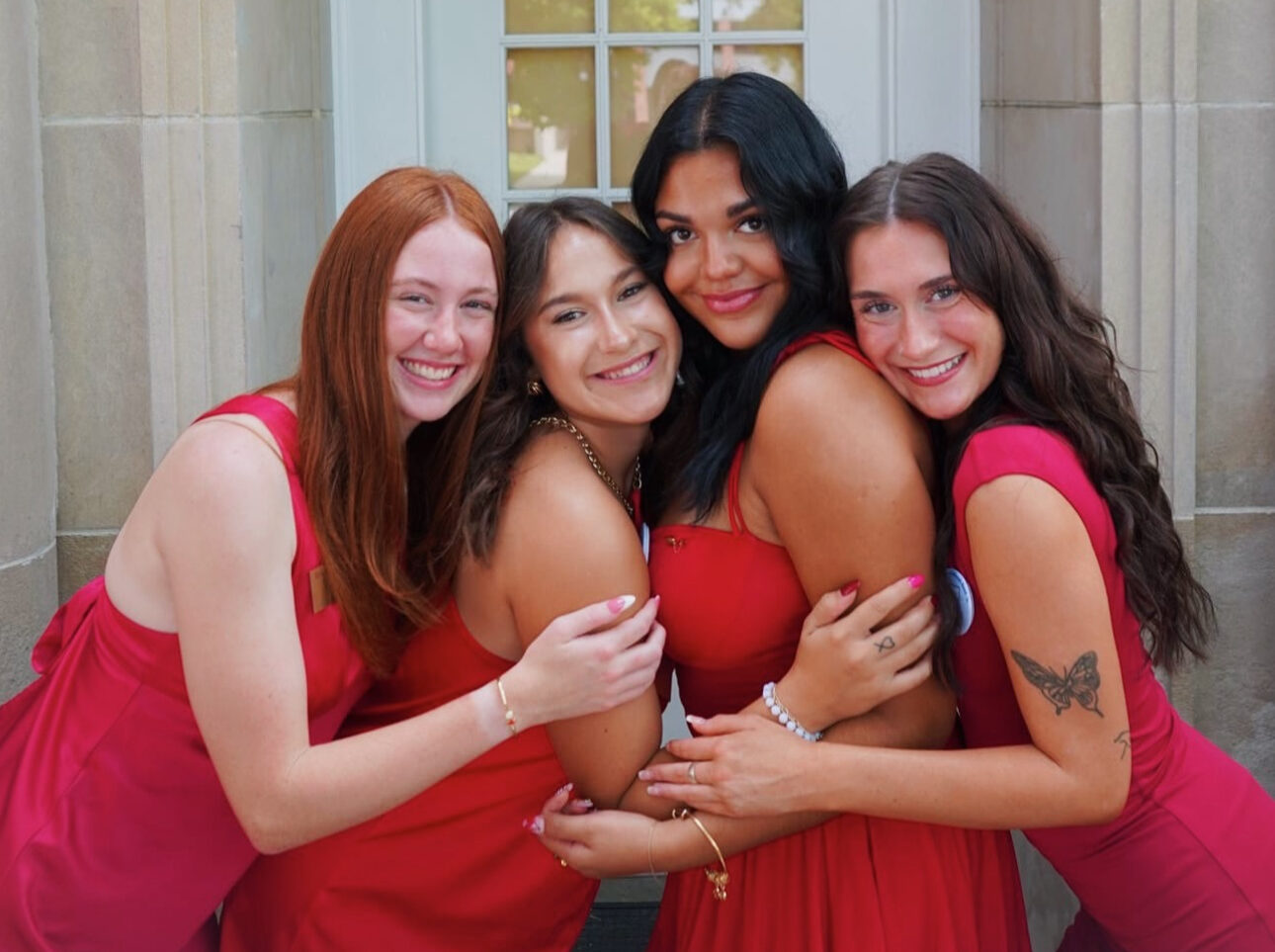 Four members wearing red standing in front of a door